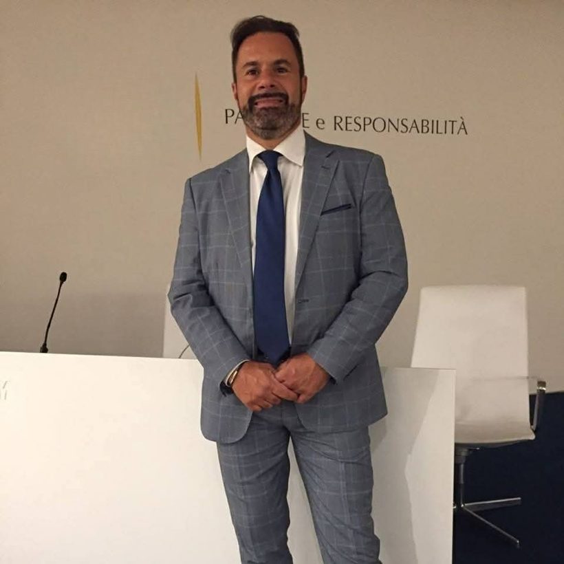 Emanuel Fiaschetti in giacca e cravatta durante un convegno